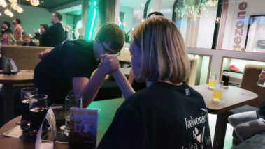 Zwei beim Armdrücken im Lokal, Drinks auf dem Tisch.