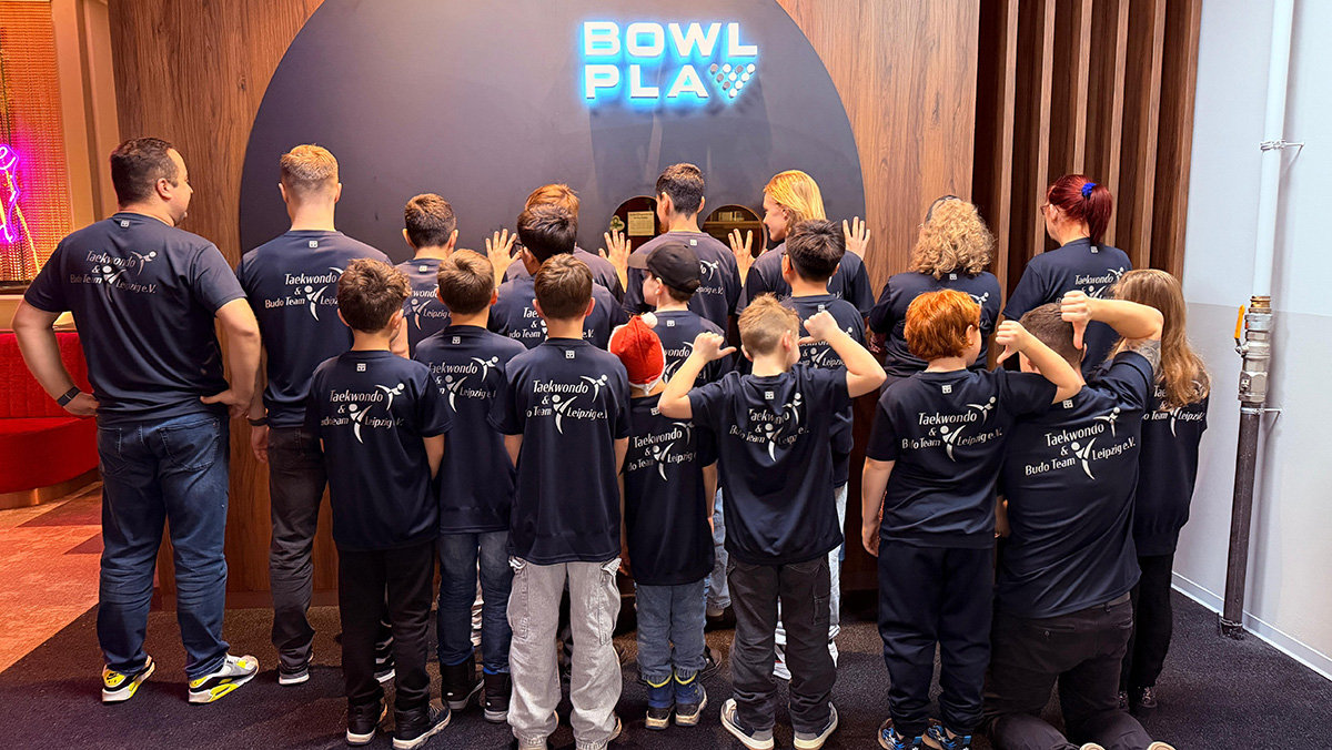 Gruppe mit Teamshirts vor „BOWL PLAY“-Wand, gemeinsamer Ausflug mit Taekwondo & Budo Team Leipzig.
